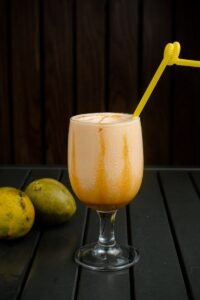 A glass with a yellow straw next to some fruit